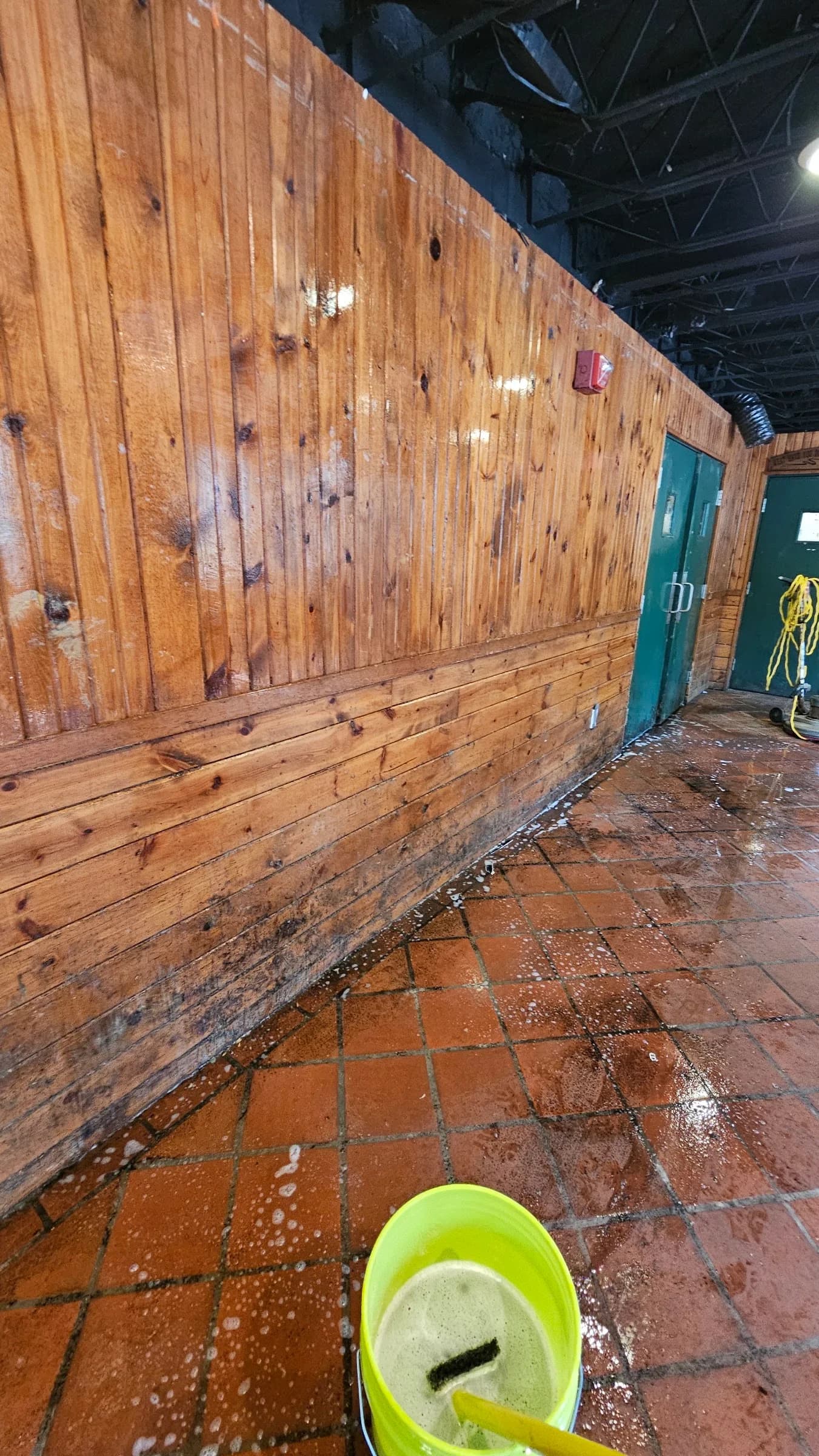 Wood-paneled hall before restoration, floor buried under debris and stains