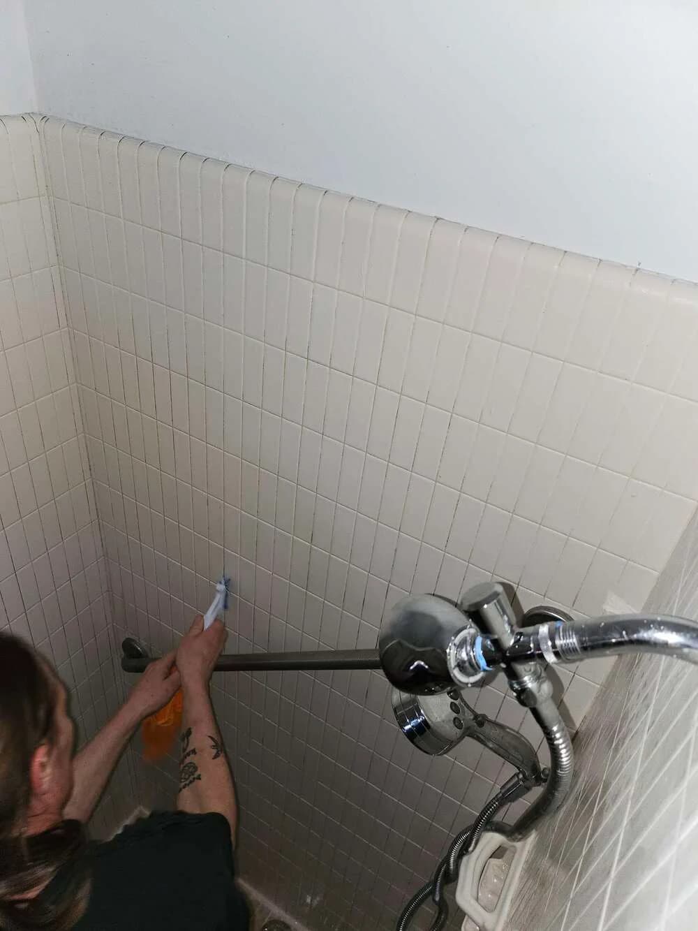 Technician hand-scrubbing a tiled wall