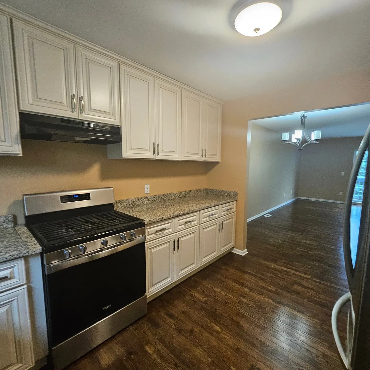 Kitchen with cream cabinets, clear stone-pattern counters, a gas range and wood-look flooring